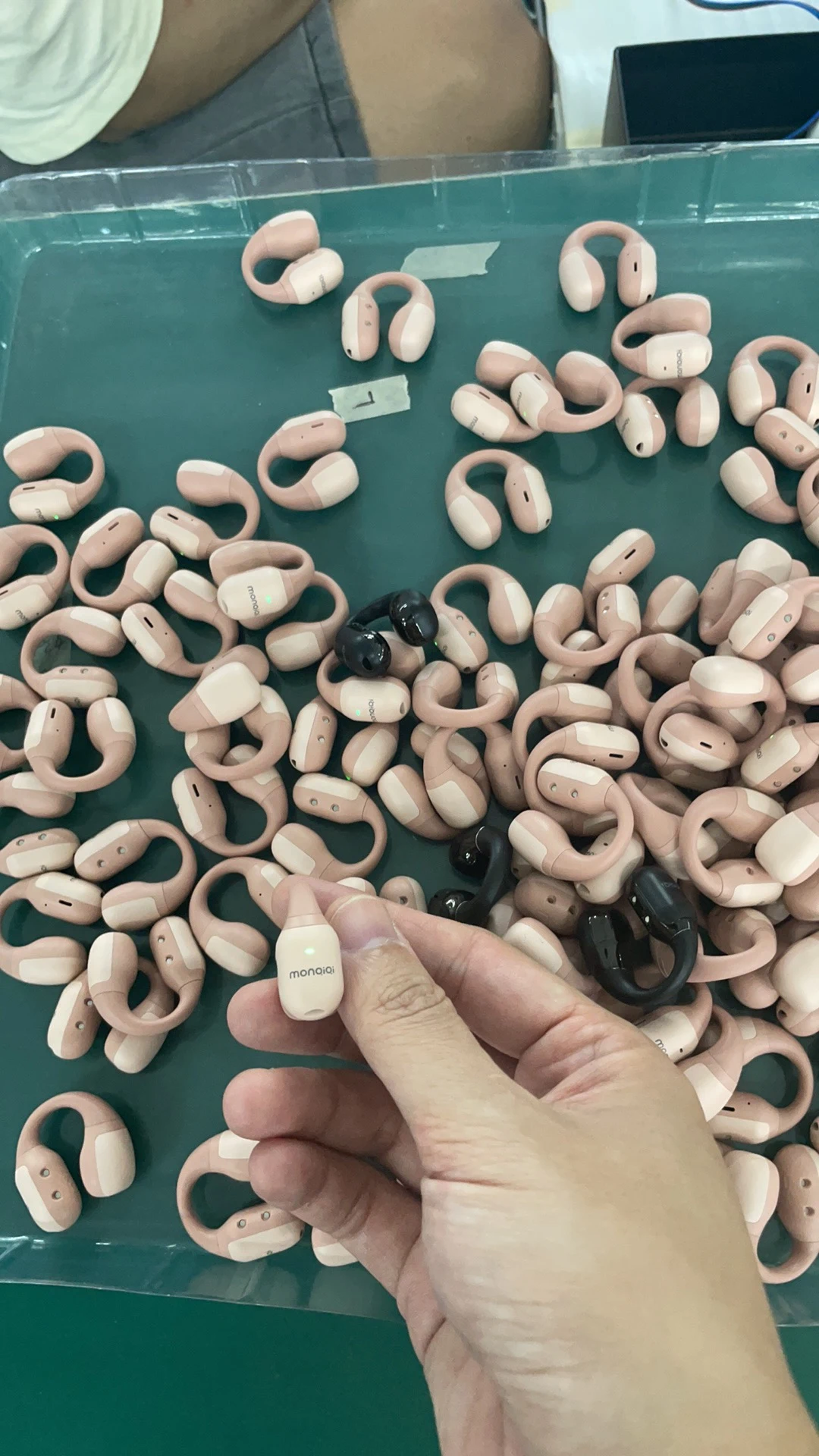 An operator handles an individual earpiece among a group of similar parts on the work surface. This close-up shows the scale of the components and the manual handling involved before the product is complete. Earpiece shape and finish vary across the catalogue; model-specific photographs show the options available for your selection.